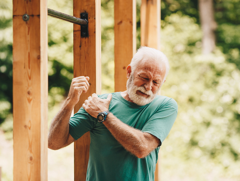 Älterer Mann greift sich beim Sport an schmerzenden Oberarm